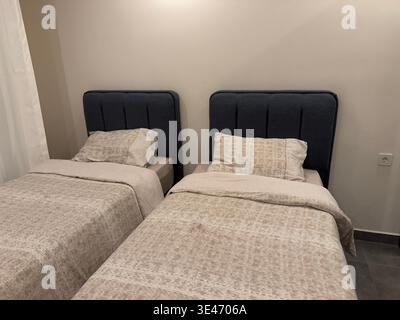 Letti gemelli in una camera moderna dalle tonalità neutre e con biancheria intima, ideale per l'ospitalità. Foto mobile Foto Stock