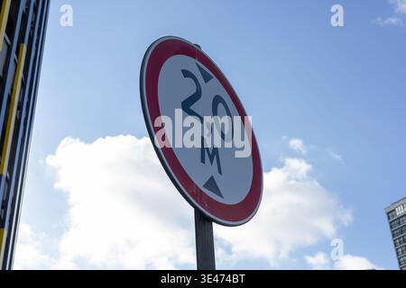 Cartello di distanza ravvicinata contro il cielo, angolo urbano con segnaletica circolare montata su polacchi, bordo rosso e nero Foto Stock