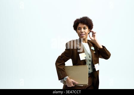 Una bella donna con un abbigliamento elegante si posa con sicurezza con un notebook e un look elegante. Foto Stock