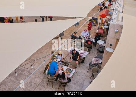 I visitatori apprezzano i ristoranti all'aperto nel quartiere storico di al Seef. Vista aerea dei tavoli da ritrovo e caffè sotto le vele ombreggiate Foto Stock