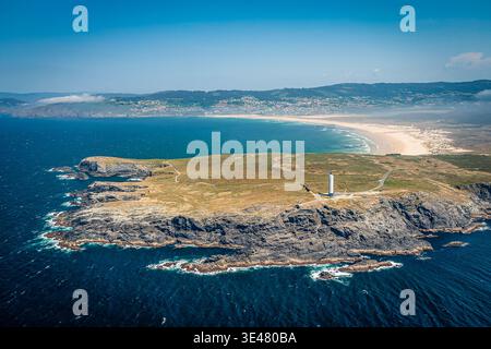Fotografia aerea di un faro solitario su un promontorio roccioso, con ampie scogliere, mare turchese, Valdovino, Spagna Foto Stock