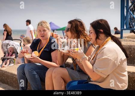 Regno Unito, Inghilterra, Lincolnshire, Mablethorpe, spiaggia, donne che mangiano gelati nelle giornate calde Foto Stock