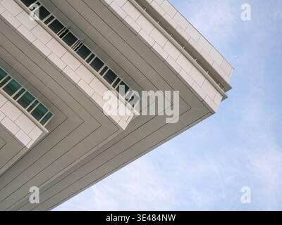 Vista verso l'alto di un moderno angolo bianco dell'edificio caratterizzato da forti linee geometriche contro un cielo blu. La scena rappresenta un architetto aziendale minimalista Foto Stock