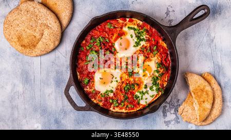 Shakshuka in una padella. Le uova in camicia in pomodoro piccante salsa di pepe. Foto Stock