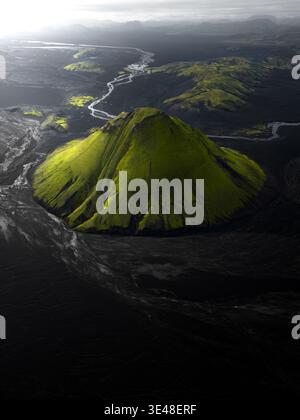 Vista aerea del vulcano Maelifell ricoperto di muschio verde circondato da campi di lava nera e da un tortuoso fiume a Skaftarhreppur, Islanda. Foto Stock