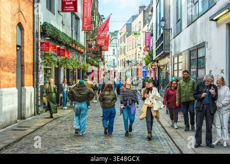 Persone che camminano attraverso Temple Bar Street con decorazioni festose per il giorno di San Patrizio nel centro di Dublino, Irlanda. Foto Stock