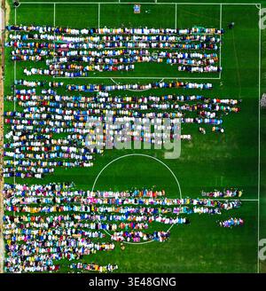 Lagos, Nigeria - 20 marzo 2026: Veduta aerea di un vivace raduno su un lussureggiante campo da calcio verde, un arazzo di vestiti colorati contro il luminoso Foto Stock