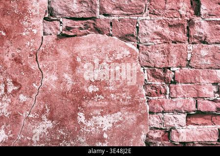 Frammento di muro di mattoni rossi con intonaco caduto e vernice sbucciante. Vecchia e sbriciolata struttura in mattoni. Sfondo grunge Foto Stock