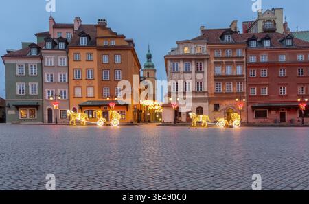 Case colorate della città vecchia e decorazioni natalizie illuminate a Varsavia, Polonia, all'alba con un'atmosfera invernale festosa. Foto Stock