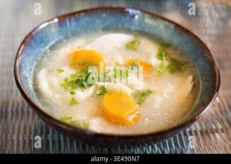 Brodo con gnocchi, carote e prezzemolo in un recipiente decorativo. Foto Stock