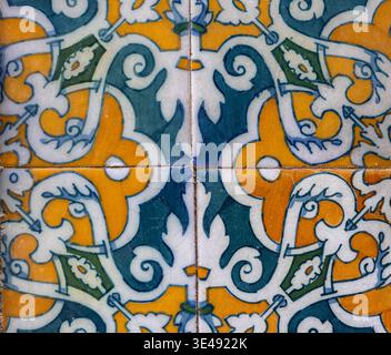 Piastrelle in ceramica ornate con design simmetrico blu e giallo Foto Stock