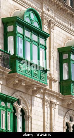 Vista dei tradizionali balconi verdi in legno su una facciata storica in pietra calcarea a la Valletta, Malta. Foto Stock