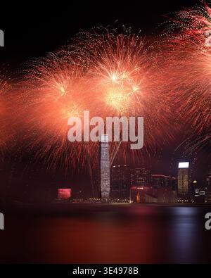 Vista dei vivaci fuochi d'artificio rossi e arancioni che esplodono sullo skyline di Victoria Harbour e l'International Commerce Centre di notte a Hong Kong. Foto Stock