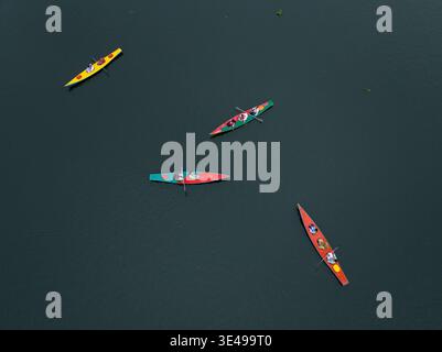 Vista aerea di kayak colorati che attraversano l'acqua scura, creando contrasti sorprendenti nel fiume, Dacca, Dacca বিভাগ, Bangladesh. Foto Stock