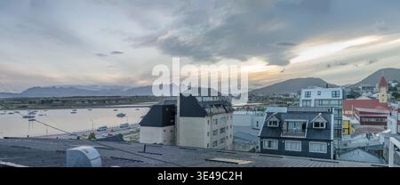 Paesaggio urbano panoramico di grandi dimensioni con tetti della città e baia sul canale di Beagle, girato con una luminosa luce nuvolosa estiva a Ushuaia, Argentina Foto Stock