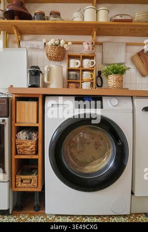 Moderna lavanderia dal design moderno con elegante lavatrice e pratiche soluzioni di stoccaggio Foto Stock