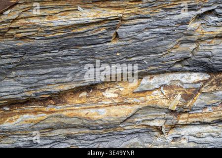 Struttura rocciosa a strati che mostra pietra ardesia naturale grigia e arancione Foto Stock
