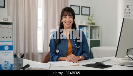 Sorriso, computer e ritratto di medico in ufficio in ospedale con fiducia nella carriera medica. Donna felice, matura e di noi con tecnologia per Foto Stock