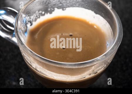 Caffè espresso scuro con crema frizzante in una tazza di vetro trasparente Foto Stock