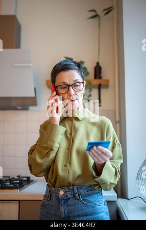 Donna anziana preoccupata che parla su smartphone con truffatori finanziari, che condivide i dati personali con i furti Foto Stock