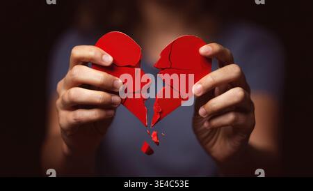 Cuore spezzato nelle mani - concetto di divorzio. foto con cuore rosso. Foto Stock