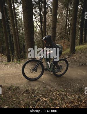 Ciclista che percorre un sentiero buio nella foresta Foto Stock