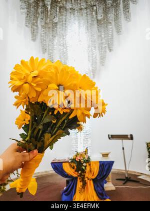 bouquet nuziale di margherite gialle nella sala per matrimoni. un piccolo bouquet di fiori selvatici autunnali nelle mani della sposa Foto Stock