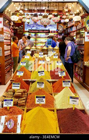 Le persone curiosano tra le colorate esposizioni di spezie nel Grand Bazaar di Istanbul. Molte spezie sono disposte in tumuli in vendita. Foto Stock