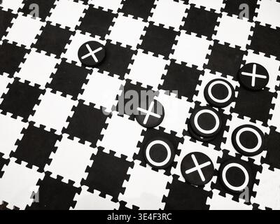 Una scacchiera in bianco e nero con X e OS viene assemblata come un gioco da terra. Foto Stock