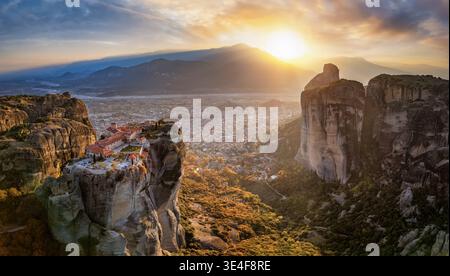 Vista aerea al tramonto delle montagne Meteora con il monastero di Agia Triada e la città di Kalabaka nella valle alle spalle, in Grecia Foto Stock