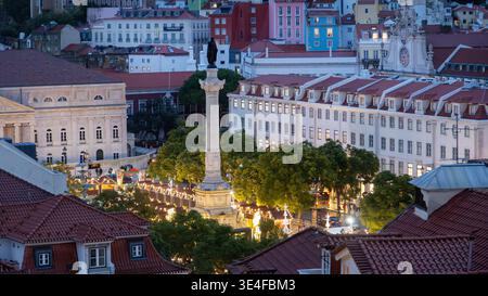 Vista sopraelevata della piazza della città con monumento e mercatino di Natale illuminato nel paesaggio urbano serale, nel centro di Lisbona in Portogallo. Foto Stock