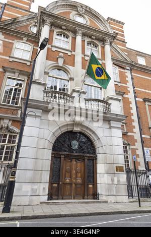 Vista dall'angolo basso dell'edificio dell'Ambasciata del Brasile a Londra, con la bandiera nazionale che sventola sopra una grande entrata ad arco in legno. Londra, Regno Unito, 14 aprile Foto Stock