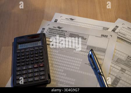 Moduli tedeschi per l'imposta sul reddito per il 2022 con una calcolatrice e penna, che rappresentano la pianificazione finanziaria Foto Stock
