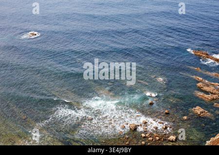 Una vista tranquilla della costa rocciosa delle Asturie, in Spagna, che mostra le dolci onde che incontrano il litorale frastagliato. Le acque cristalline evidenziano il Foto Stock