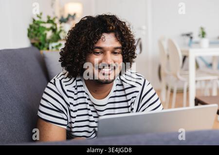 Giovane indiano felice mentre lavora con un portatile Foto Stock