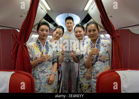 Singapore - 7 dicembre 2025: Ritratto di gruppo dell'equipaggio di cabina di Hainan Airlines, inclusi gli assistenti di volo e un steward, che posa all'interno di un Boeing 737-80 Foto Stock