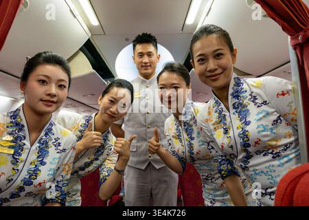 Singapore - 7 dicembre 2025: Ritratto di gruppo dell'equipaggio di cabina di Hainan Airlines, inclusi gli assistenti di volo e un steward, che posa all'interno di un Boeing 737-80 Foto Stock