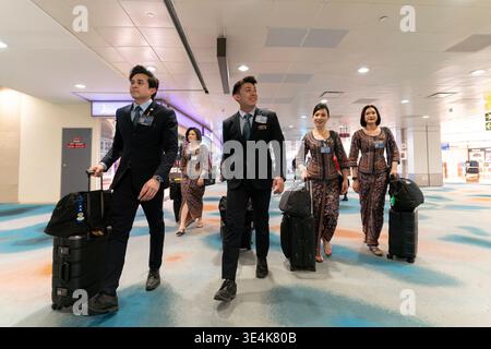 Singapore - 9 dicembre 2025: Un gruppo di membri di cabina della Singapore Airlines, di cui due maschi e quattro femmine, attraversa l'aeroporto di Changi con spirito Foto Stock