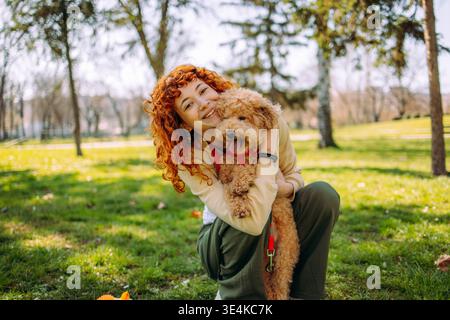 Donna allegra che passa del tempo con un cane simpatico e giocoso nel parco Foto Stock