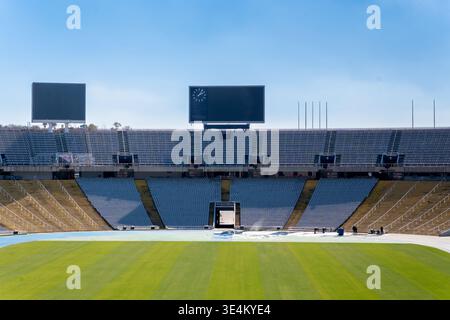Vista ravvicinata della sezione centrale dei posti a sedere in uno stadio di Barcellona con campo verde, tabelloni segnapunti e banchi vuoti alla luce del giorno. Foto Stock