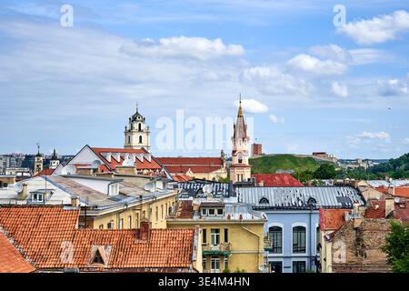 Una vista panoramica della città Vecchia di Vilnius che mostra un mare di tradizionali tetti di terracotta rossa in primo piano. Due importanti torri della chiesa sorgono Foto Stock