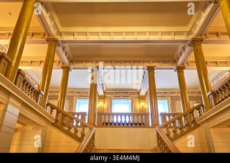 Vista interna di un grandioso edificio neoclassico caratterizzato da una doppia scala ornata con balaustre di legno che convergono ad un atterraggio centrale. Il Foto Stock