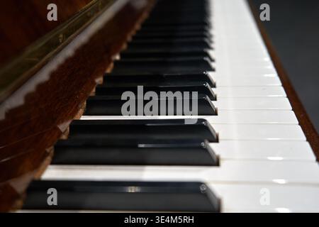 Vista in diagonale ravvicinata di una tastiera a pianoforte che mostra il classico schema dei tasti in bianco e nero. La fotografia cattura la superficie lucida di Foto Stock