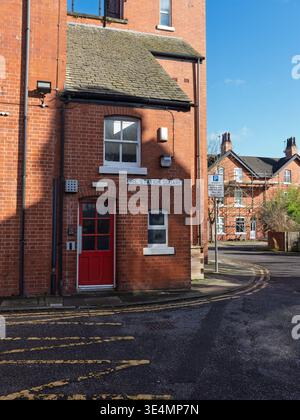 Salford, Manchester, Regno Unito, 28 marzo 2026: Affascinante caserma dei pompieri in mattoni a Salford Manchester con una porta rossa in un tranquillo quartiere urbano. Foto Stock