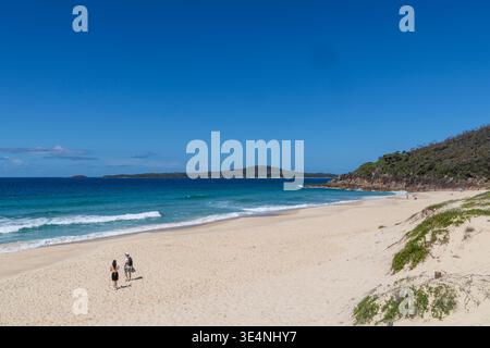 Giovane coppia che cammina sulla sabbia bianca della spiaggia di Zenith, del parco nazionale di Tomaree, di Port Stephens, nuovo Galles del Sud, Australia Foto Stock