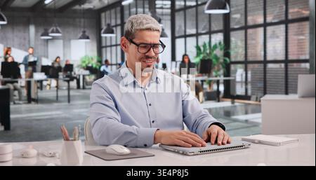 Uomo d'affari sopraffatto che chiude il notebook in mezzo allo stress dei cyber attacchi Foto Stock