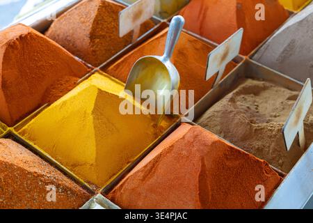 Un variopinto assortimento di spezie disposte in tumuli ordinati presso una bancarella del mercato orientale. Questo vivace spettacolo cattura l'essenza di un bazar tradizionale, perfetto per progetti culinari, di viaggio e culturali Foto Stock