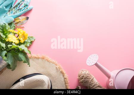 Sfondo di giardinaggio con gerbera, pedaggi e impianto di fiori nella casella su sfondo giallo. Vista da sopra. Spazio per il testo. Foto Stock