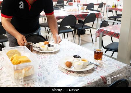 Un gran numero di piatti per la colazione per bambini a scuola o dipendenti di aziende. Su un piatto di uova, miele, formaggio e formaggio fresco. Il cameriere Foto Stock