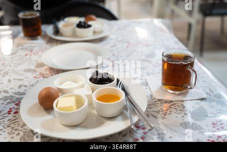 Un gran numero di piatti per la colazione per bambini a scuola o dipendenti di aziende. Su un piatto di uova, miele, formaggio e formaggio fresco Foto Stock